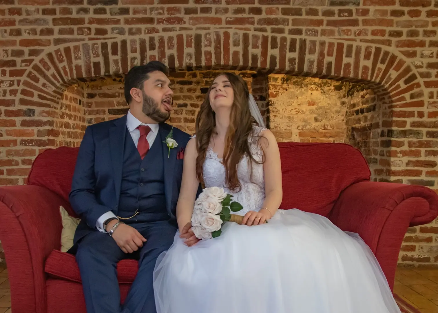 Bride and groom relaxing for photos by the fireplace at Leez Priory