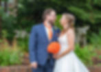 bride with orange bouquet and groom in navy suit with orange tie