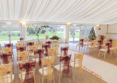 The Fennes marquee set up for a Christmas wedding ceremony with red accents and a Christmas Tree