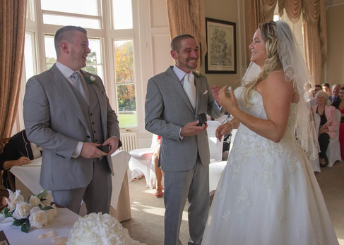 Bride and groom exchange rings in the sunbathed drawing room of Wivenhoe House Hotel