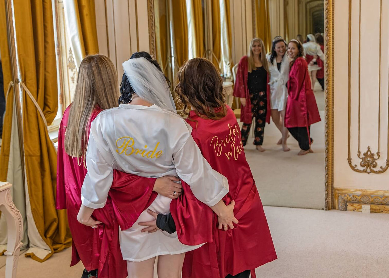 Bride grabs her bridesmaids bums for a photo during preps at Gosfield Hall in Essex