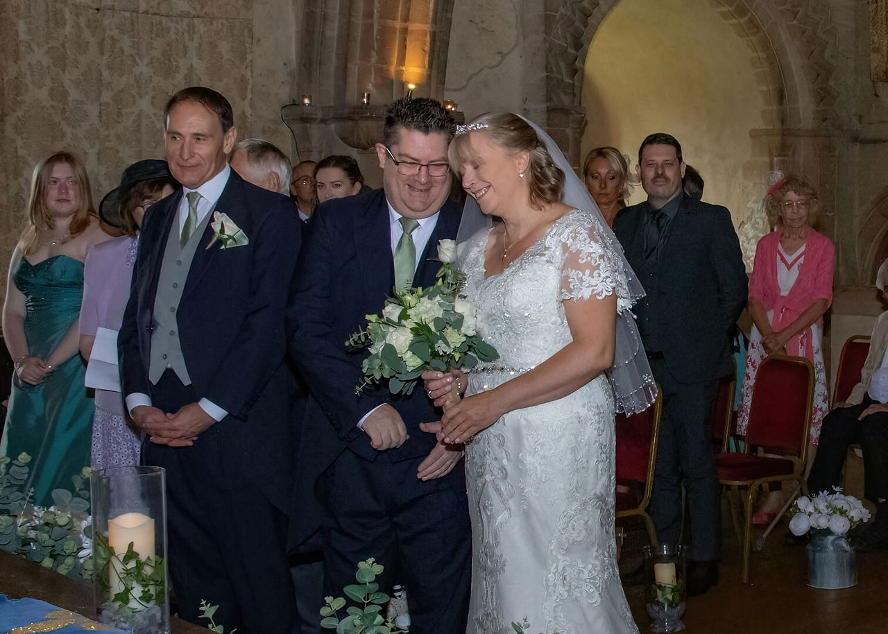 Bride and groom share an intimate giggle during their wedding ceremony at Hedingham Castle in Essex