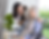 Caregiver smiles at elderly woman in a wheelchair by a window, with RW HealthCare logo and potted plant in a bright room.