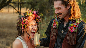 Groom wearing floral lapel feeding bride wearing a large floral headpiece a large piece of cake