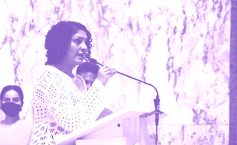 Karina speaking at a podium with the audience looking on