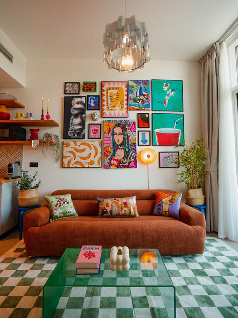 Living room with mix-and-match framed prints, low oak coffee table, and layered cushions in warm tones
