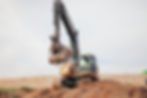 An excavator with the scoop full of dirt, driven by a construction worker in Burleson, TX