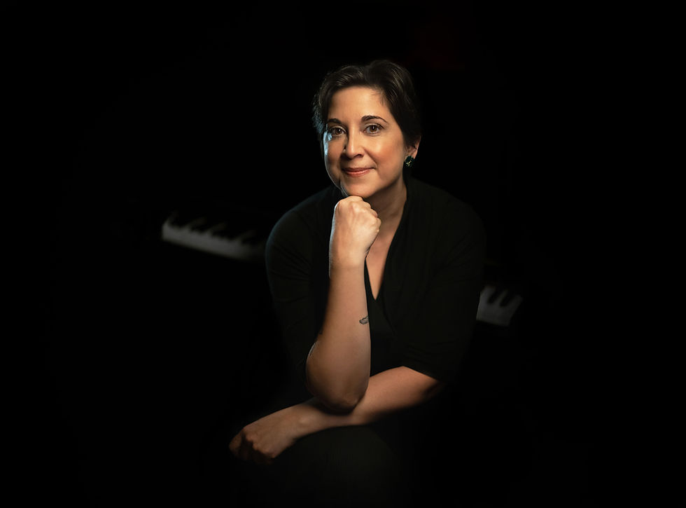 Kamala leans forward, chin resting on her hand, and smiles at the camera.