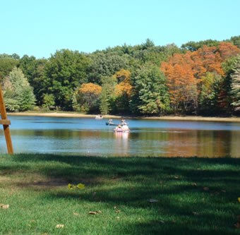 Person kayaking on lake at Muskegon Campground in late summer
