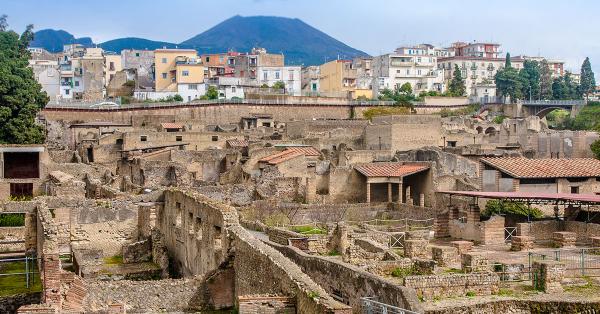Runtuhan Kota Kuno Herculaneum di tengah bangunan-bangunan baru, di belakangnya Gunung Vesuvius. (Pfeiffer/Shutterstock).