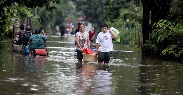 Warga membawa barang-barang melewati banjir di Jakarta. (Fernando Randy/Historia).