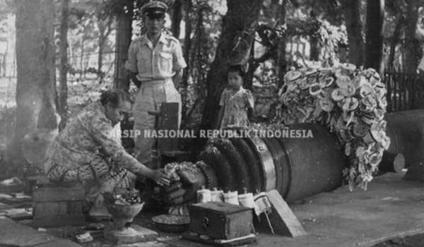 Seorang perempuan sedang membakar menyan dan menaburkan bunga ke meriam Si Jagur tahun 1951. (ANRI)