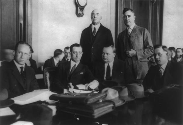 Roscoe Arbuckle (duduk ketiga dari kanan) bersama para pengacara pembelanya di persidangan pertama terkait kematian aktris Virginia Rappe tahun 1921. (Wikipedia).