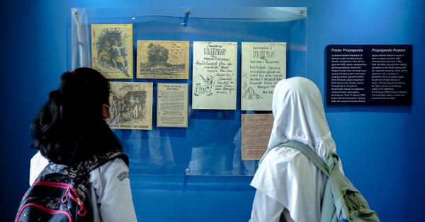 Dua siswi saat melihat poster propaganda Jepang pada pameran Sakura di Khatulistiwa. (Historia.ID/Fernando Randy).