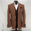 Thumbnail: A brown herringbone tweed blazer displayed at a three-quarter angle, showcasing the layered look with a dark brown waistcoat