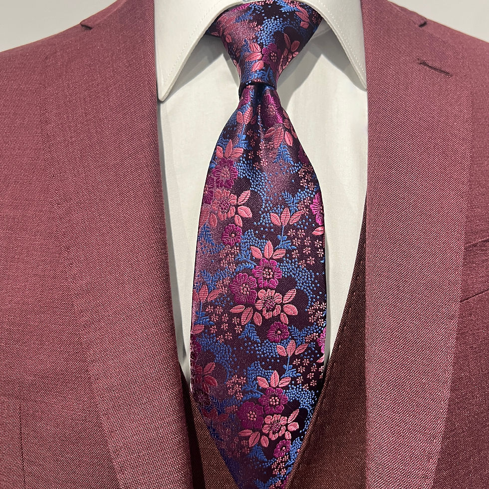 A close-up of a navy silk tie with an intricate floral pattern in shades of pink and magenta, elegantly paired with a matchin