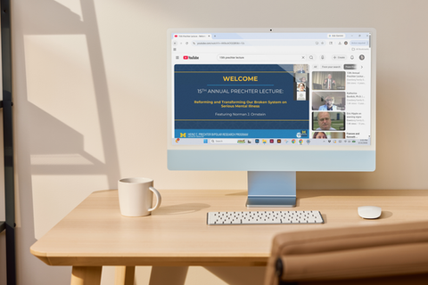 Computer on desk displaying online lecture video.