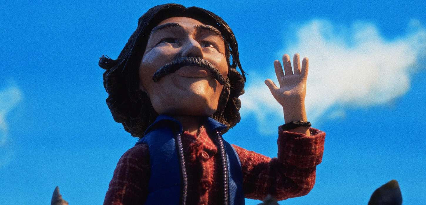 Stop-motion sailor character waving against blue sky in Give Me Love music video