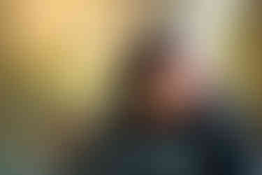 A girl in glassing smiling with her hair flowing has she shakes her head.