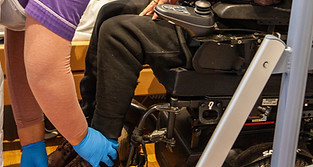 two carers assisting a man in a wheelchair