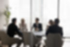 Group of businesspeople negotiating gathered in modern conference room, blurred silhouette