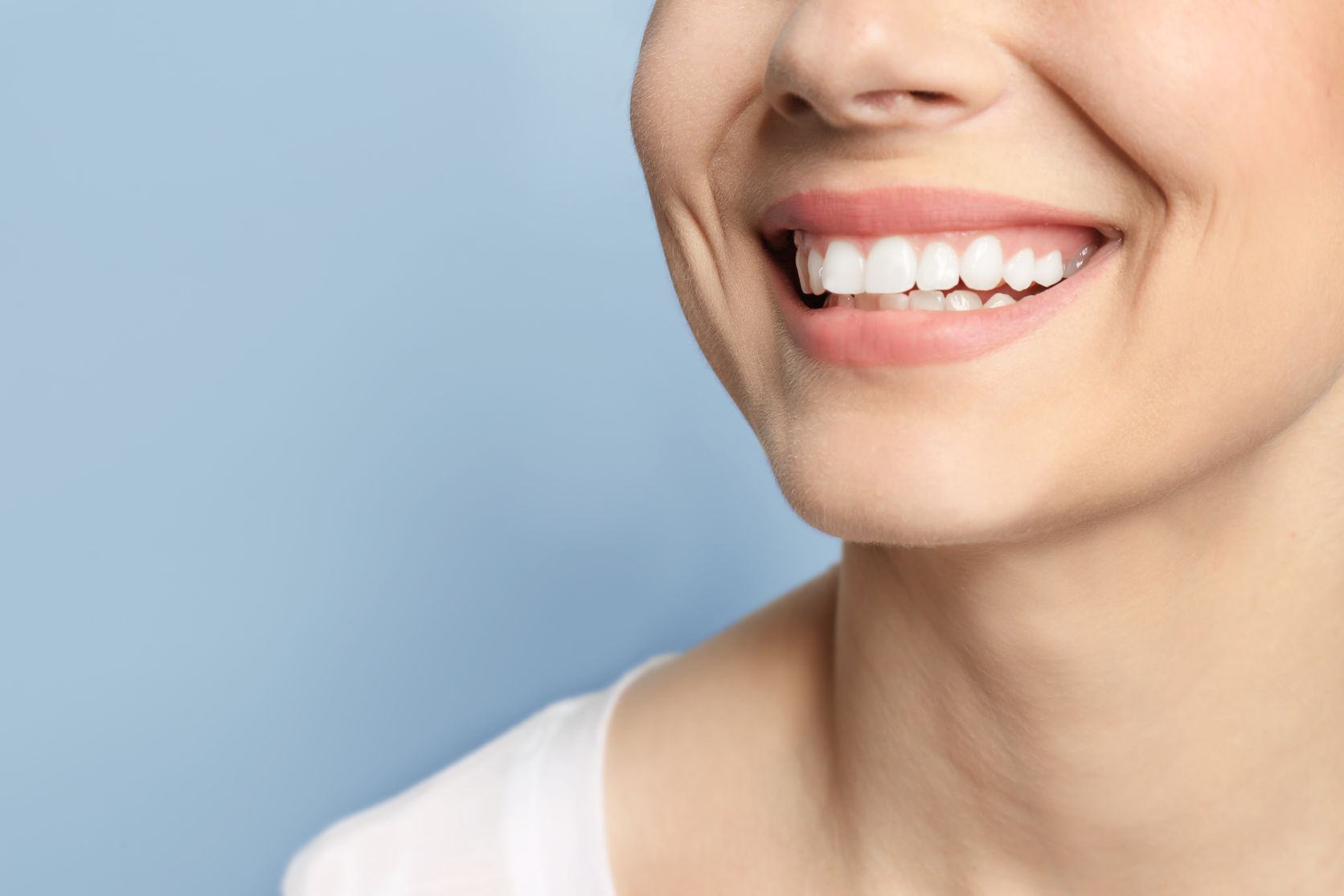 Young woman with beautiful smile on grey background. Teeth whitening.jpg