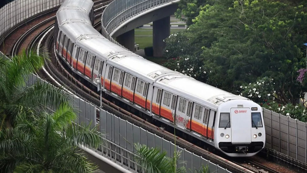 A train with an orange stripe travels on elevated tracks amidst lush greenery. The train is marked with SMRT logos, conveying efficiency and modernity.