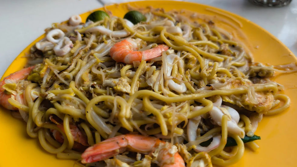 Noodles with shrimp, squid, and lime on a yellow plate. The dish appears freshly cooked and appetizing, with vibrant colors.