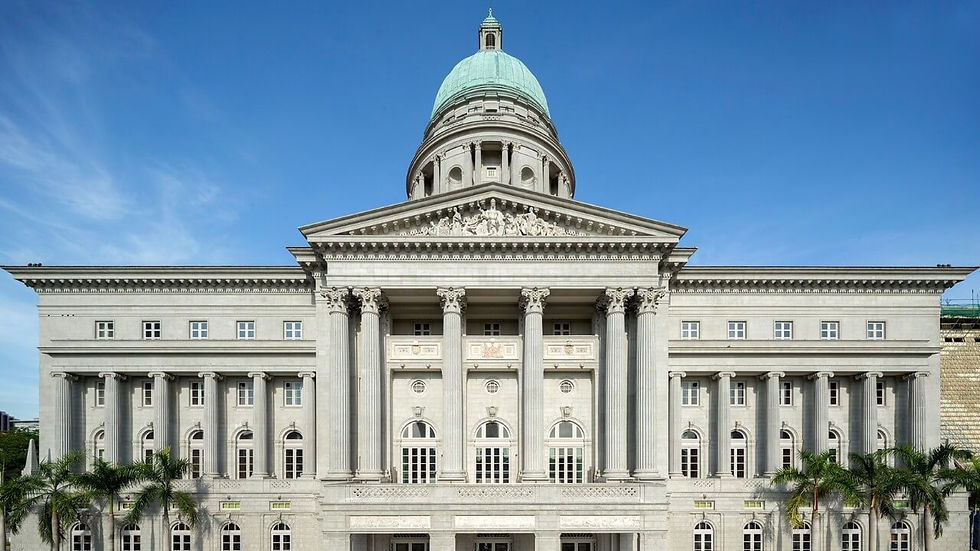 Neoclassical gray building with columns and a green dome against a clear blue sky. Palm trees line the front; ornate carvings are visible.