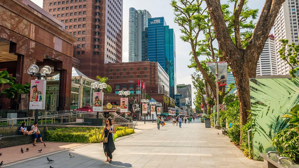 Sunny city promenade with pedestrians, pigeons, and tall skyscrapers, framed by trees and banners in a busy urban scene