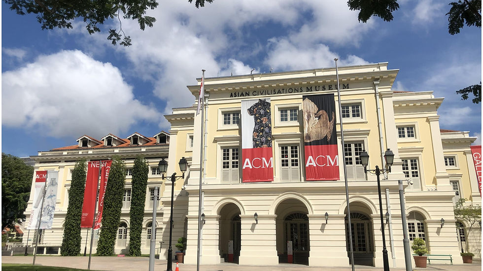 Asian Civilisations Museum facade with banners reading ACM. Classic architecture under a blue sky with white clouds and trees framing the scene.