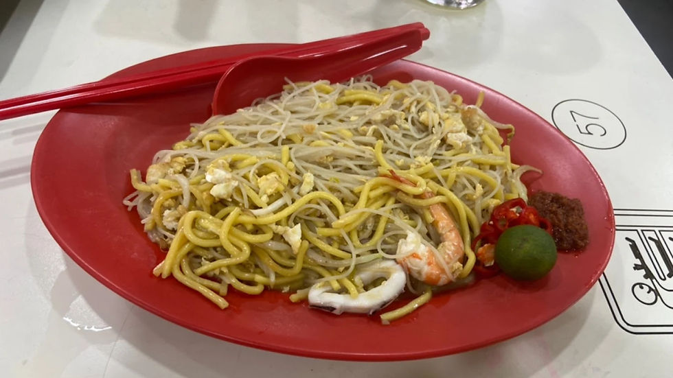 Noodles with shrimp, chili, lime, and sauce on a red plate with red chopsticks. White table with number 57 visible in the background.