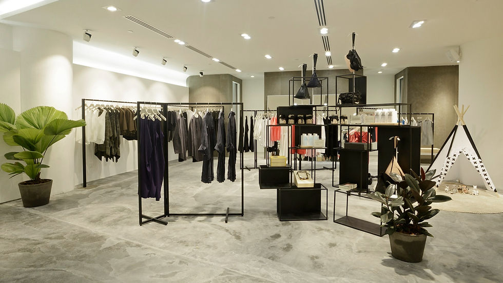 Chic clothing store interior with racks of clothes, potted plants, and a small teepee display. Soft lighting and minimalist decor.