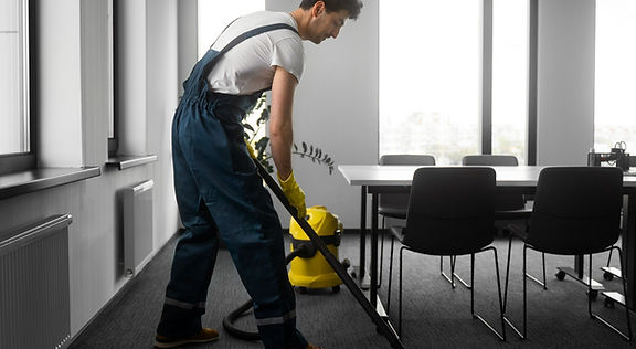 Technicien Proffi Cleaner en train de nettoyer une moquette dans un bureau avec un aspirateur professionnel.