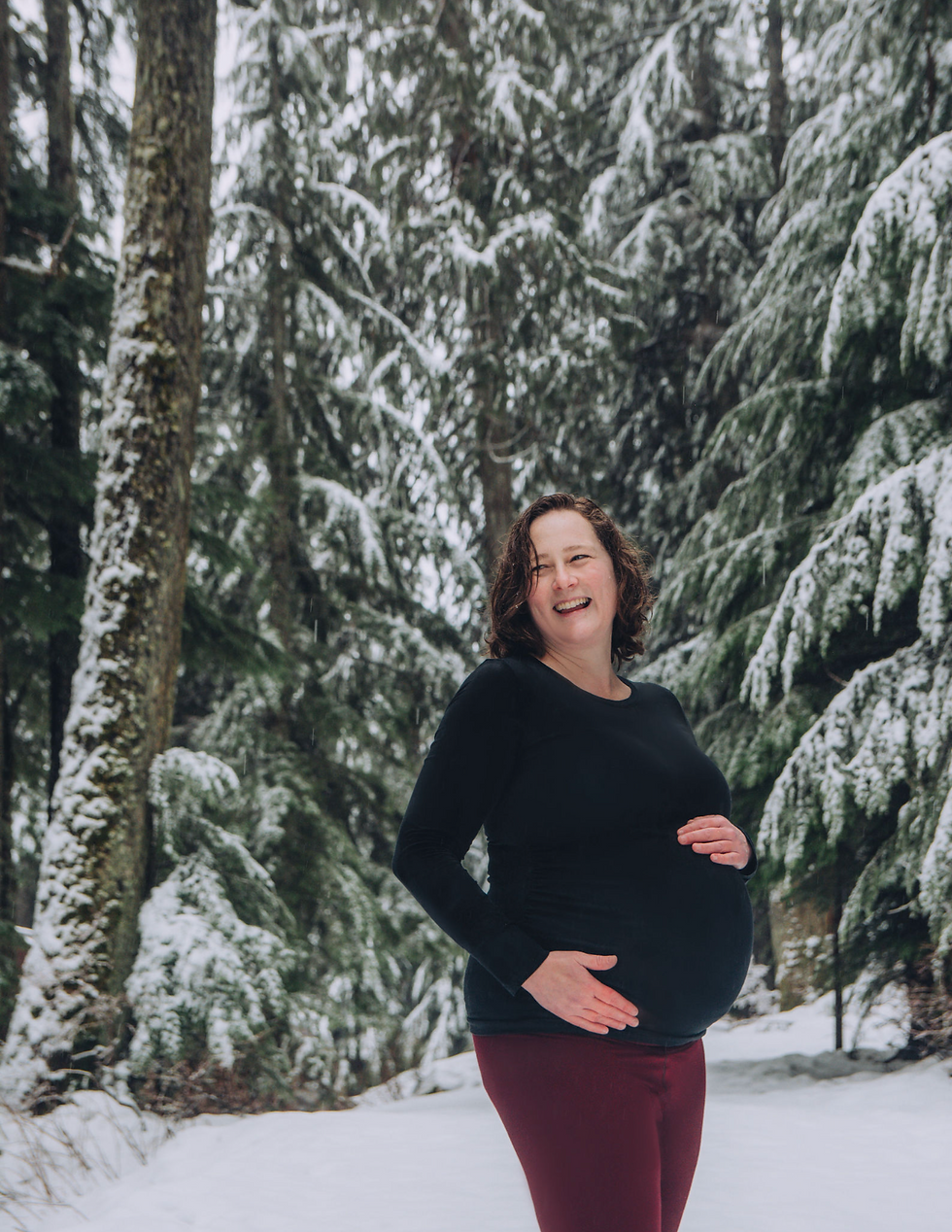 Outdoor winter maternity photo in Vancouver forest – seasonal family photography session with snow-covered trees by My City Photos.