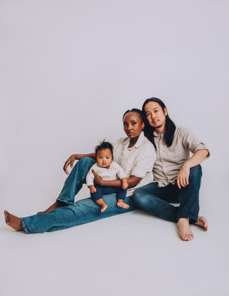 Maternity photo with parents and their newborn baby captured in a clean, neutral studio setting