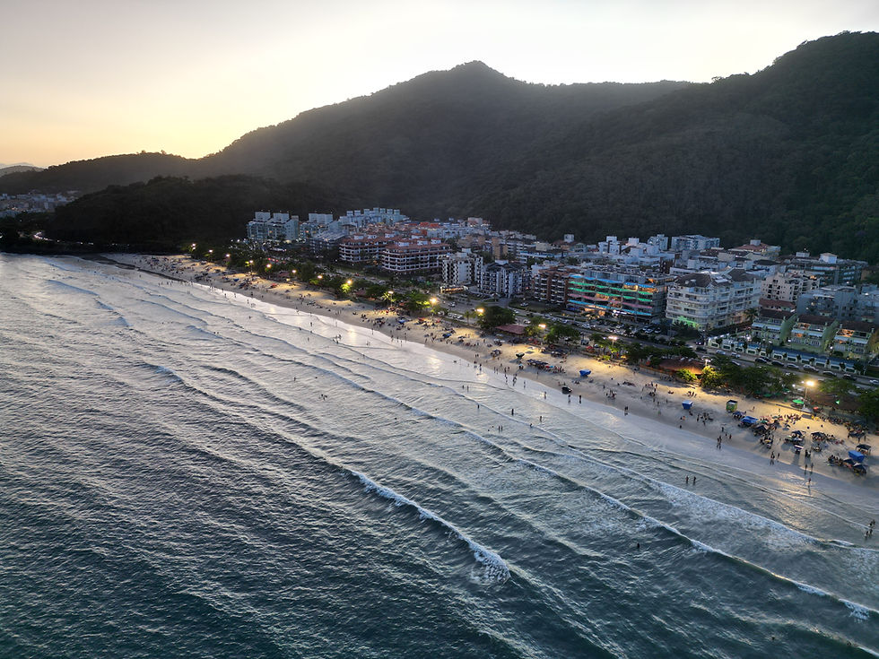 Vista aérea da Praia Grande ao entardecer, com iluminação noturna.