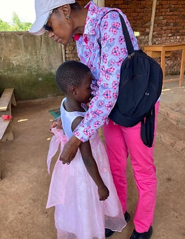 An adult fixing a bow tie at the back of a little girls dress.