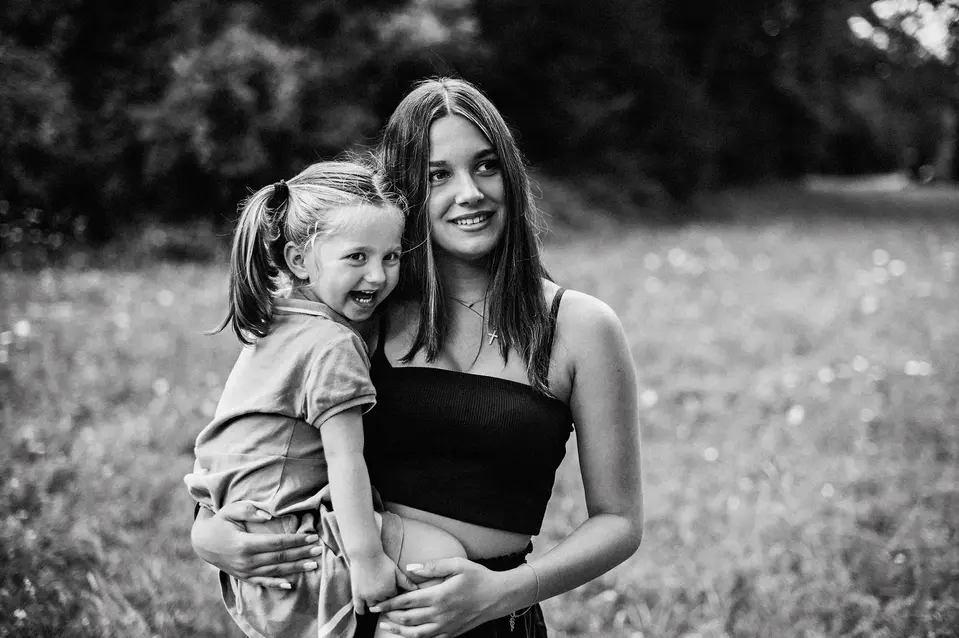 Geschwister lachen gemeinsam bei einem sommerlichen Fotoshooting im Wienerwald, aufgenommen von Pia Morpurgo
