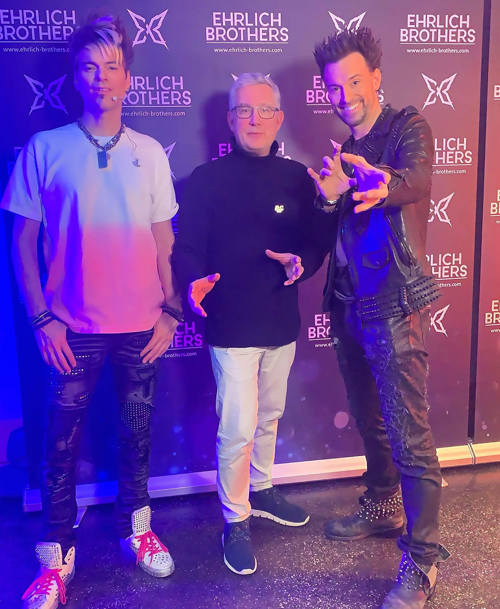 Zauberer Jonas steht gemeinsam mit den Ehrlich Brothers vor einer Eventwand bei einer Zauberveranstaltung