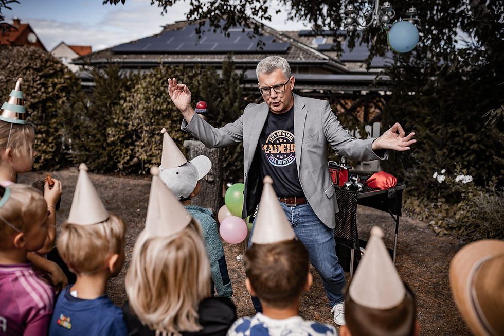 Kinderzauberer Jonas begeistert Kinder be einer Zaubershow auf einem Kindergeburtstag im Garten