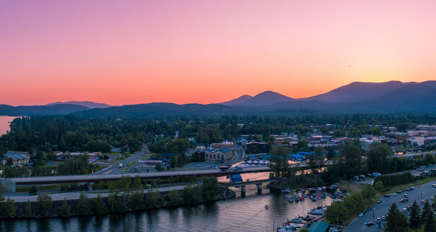 A sweeping panoramic view of a charming town nestled on a lake at golden-hour sunset
