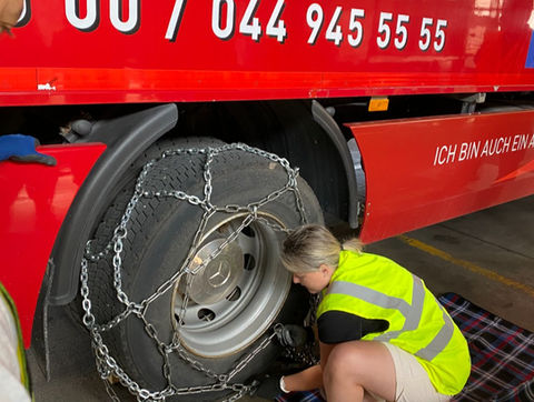 Dame montiert am Lastwagen Schneeketten am CZV Kurs