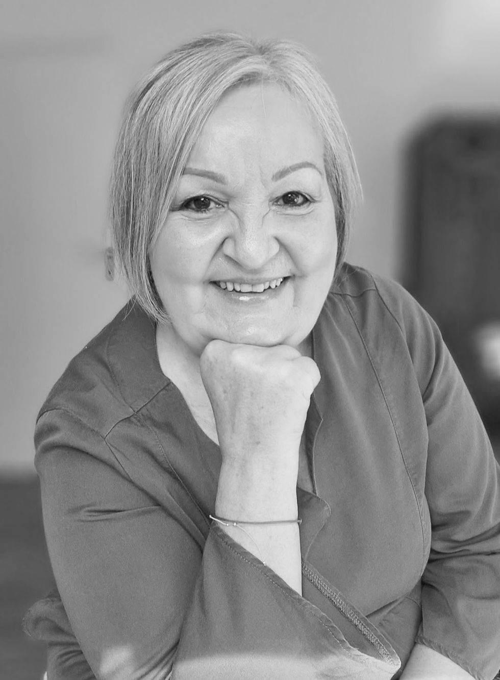 Luise Geier-Asfiaoui, schwarz-weiß, lächelnd, Kopf auf Hand gestützt
