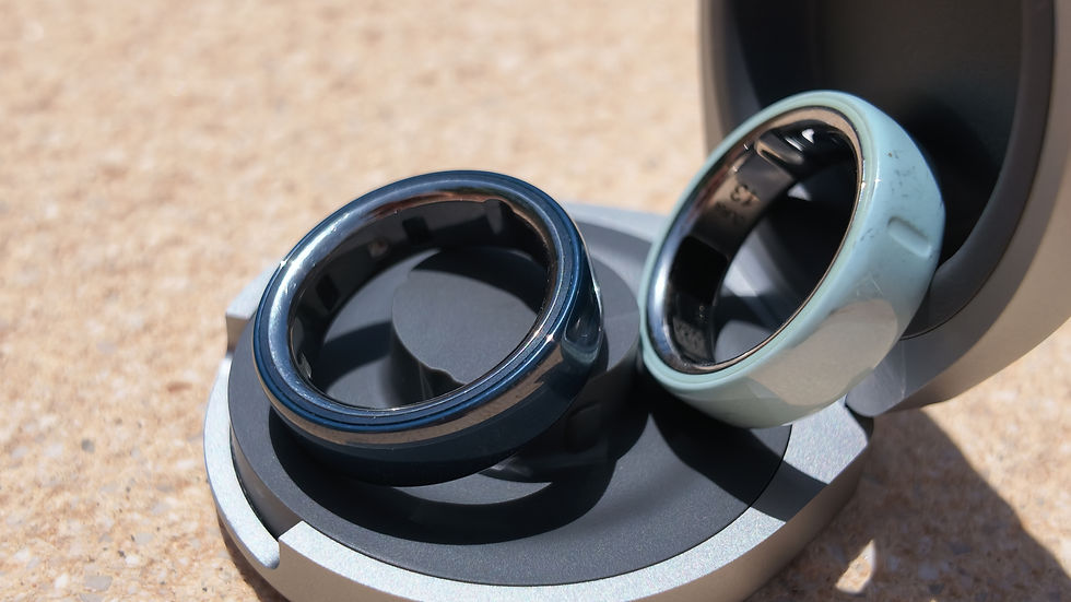 Two metallic rings, one dark blue and one pale blue, displayed on a round stand in a close-up against a beige background.