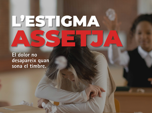 Cartell de la campanya «L’ESTIGMA ASSETJA» amb una alumna asseguda a l’aula, inclinada sobre els braços i amb el cap baix, mentre altres estudiants apareixen desenfocats al fons. El text diu «El dolor no desapareix quan sona el timbre».