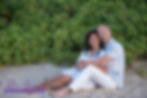 couple in front of green bushes posing for photo