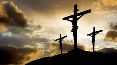 Jesus and two others on crosses on a hill with cloudy sky
