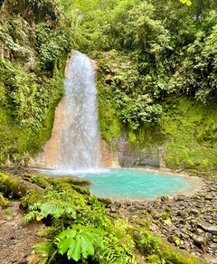 Waterfall flowing into turquoise lagoon surrounded by dense tropical forest in Costa Rica