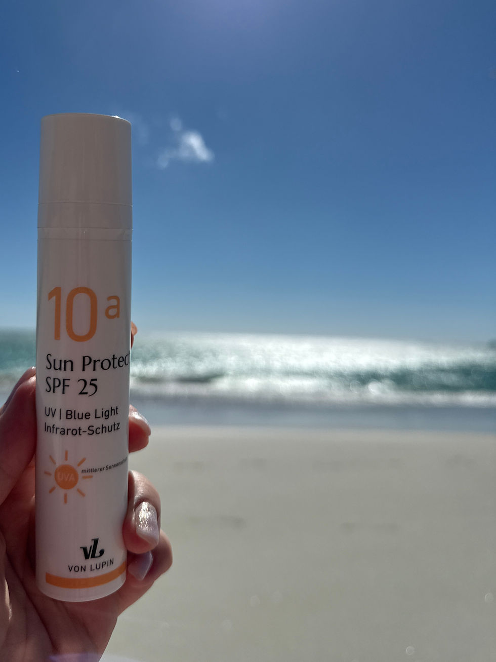 Sonnencreme gehalten in der Hand am Strand von Südafrika